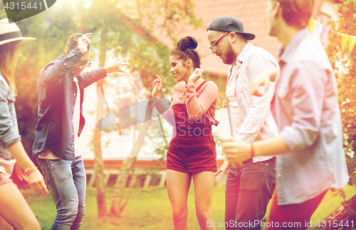 Image of happy friends dancing at summer party in garden