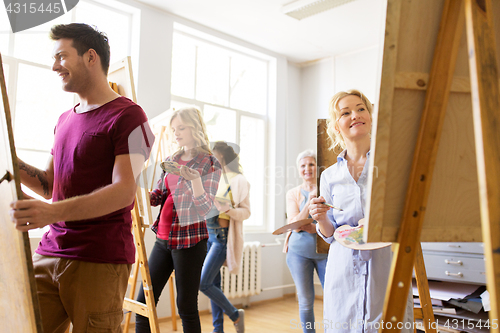 Image of artists with brushes painting at art school