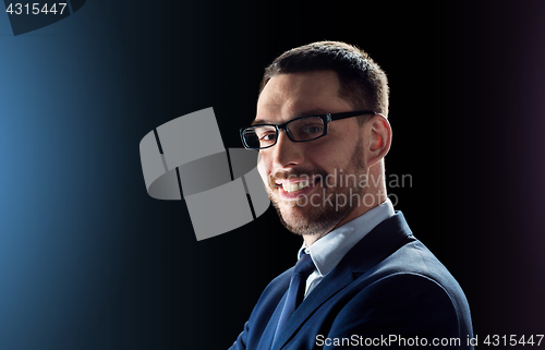 Image of smiling businessman in glasses over black