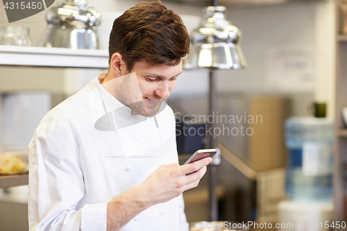 Image of chef cook with smartphone at restaurant kitchen