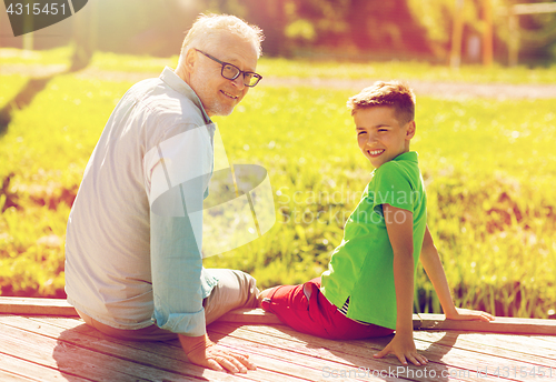 Image of grandfather and grandson sitting on river berth