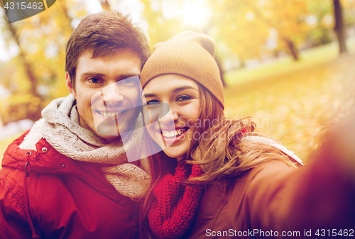 Image of happy young couple taking selfie in autumn park