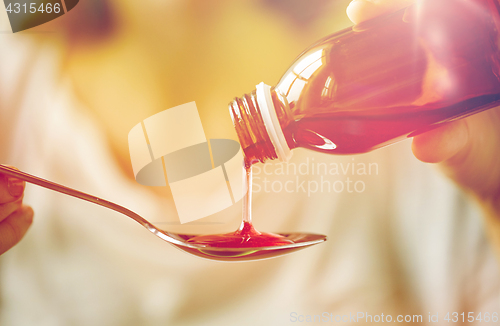 Image of woman pouring medication from bottle to spoon