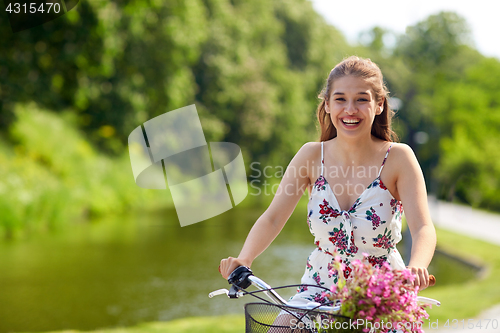 Image of happy woman riding fixie bicycle in summer park