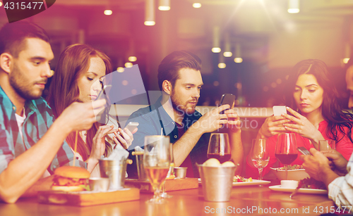 Image of friends with smartphones dining at restaurant