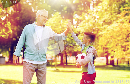 Image of old man and boy with soccer ball making high five