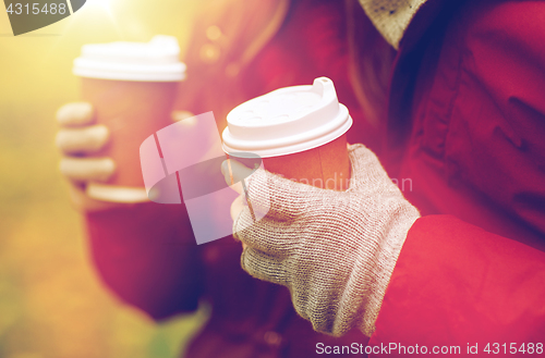 Image of close up of couple hands with coffee in autumn