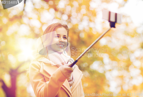 Image of woman taking selfie by smartphone in autumn park