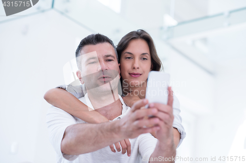 Image of happy couple using mobile phone at home