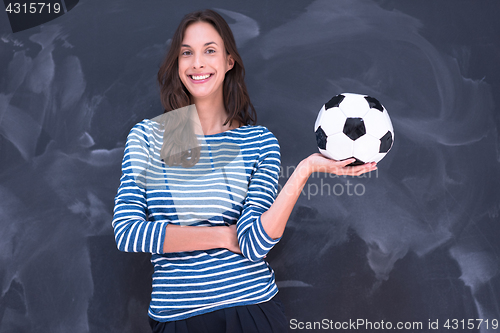 Image of woman holding a soccer ball in front of chalk drawing board