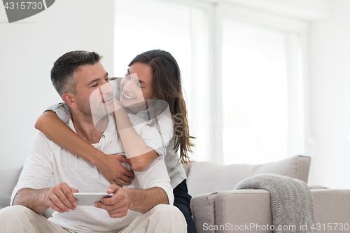 Image of happy couple using mobile phone at home