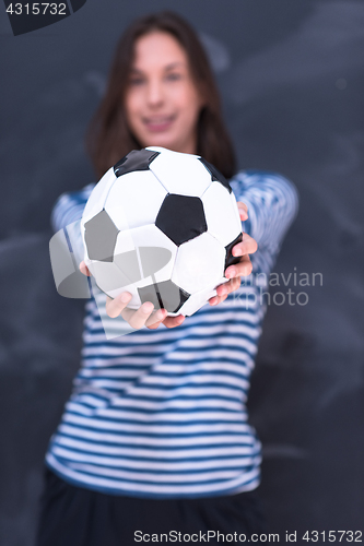 Image of woman holding a soccer ball in front of chalk drawing board