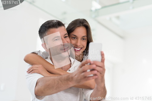 Image of happy couple using mobile phone at home