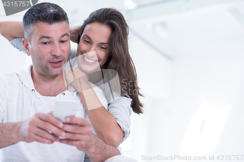 Image of happy couple using mobile phone at home