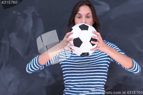 Image of woman holding a soccer ball in front of chalk drawing board