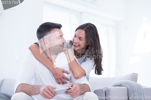 Image of happy couple using mobile phone at home