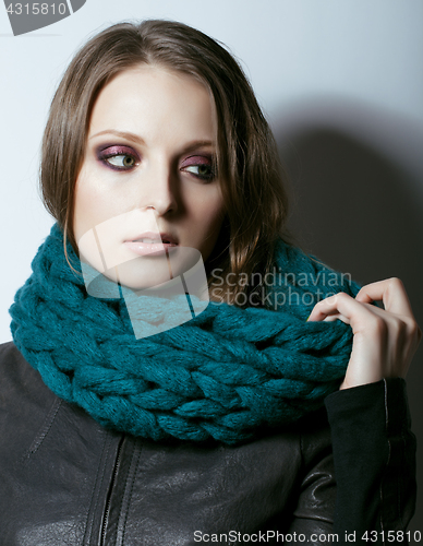 Image of young pretty real woman in sweater and scarf all over her face smiling