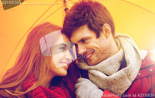 Image of smiling couple with umbrella in autumn park