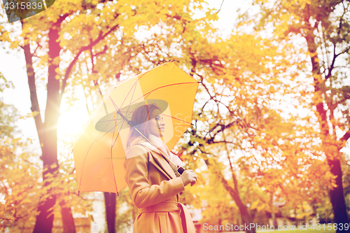 Image of happy woman with umbrella walking in autumn park