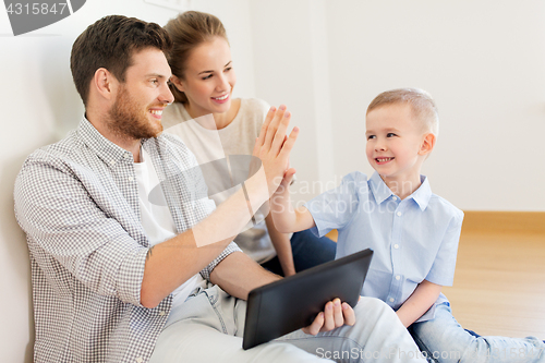 Image of family with tablet pc at new home making high five