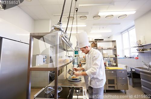 Image of happy male chef cooking food at restaurant kitchen