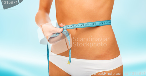 Image of close up of woman body with measure tape on waist