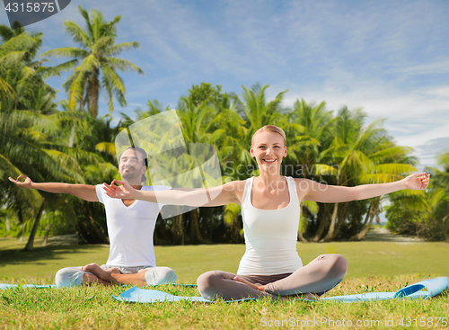 Image of couple doing yoga in lotus pose outdoors