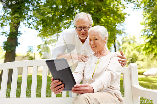 Image of happy senior couple with tablet pc in city park