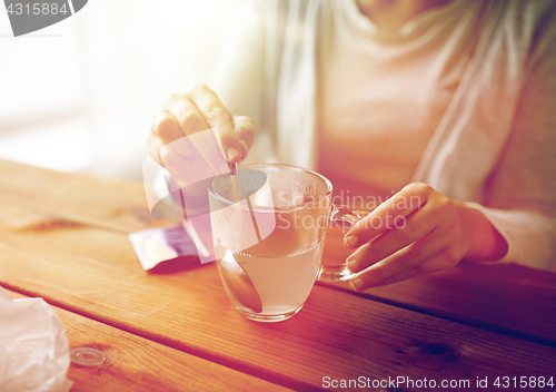 Image of woman stirring medication in cup with spoon