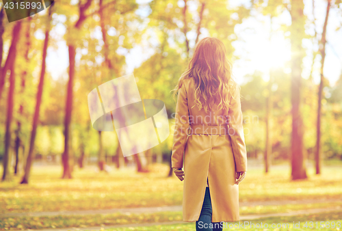 Image of beautiful young woman walking in autumn park
