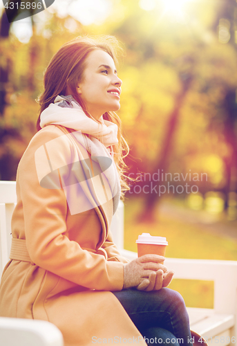 Image of happy young woman drinking coffee in autumn park