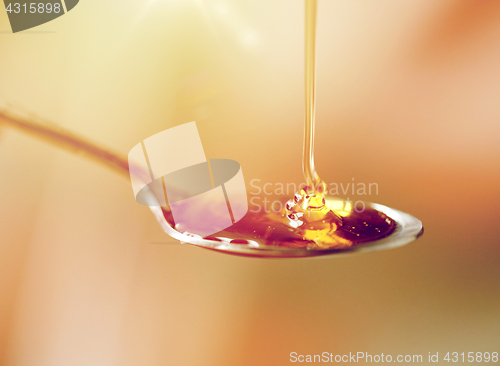 Image of close up of honey pouring to teaspoon