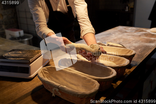 Image of baker with dough rising in baskets at bakery