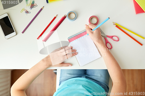 Image of girl drawing in notebook at home