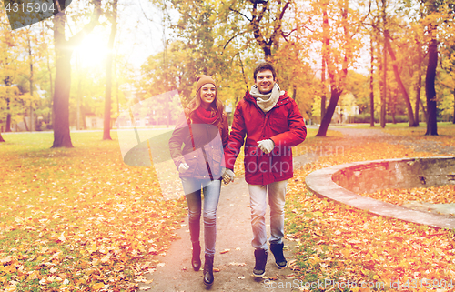 Image of happy young couple running in autumn park