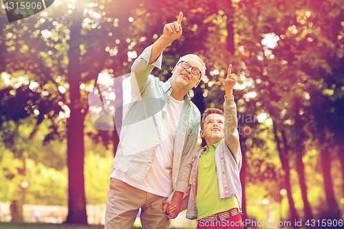 Image of grandfather and boy pointing up at summer park