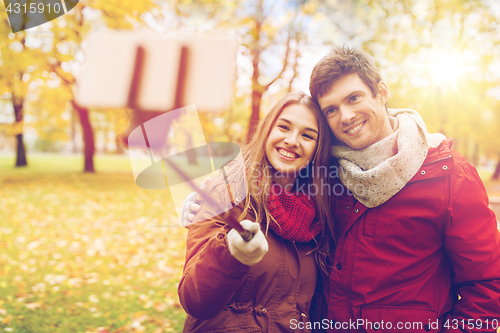 Image of couple taking selfie by smartphone in autumn park
