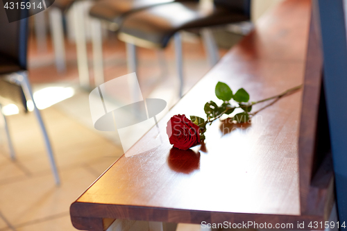 Image of red roses on bench at funeral in church