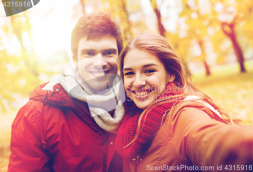 Image of happy young couple taking selfie in autumn park