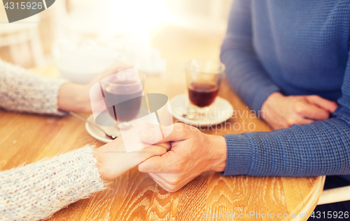 Image of close up of couple holding hands at restaurant