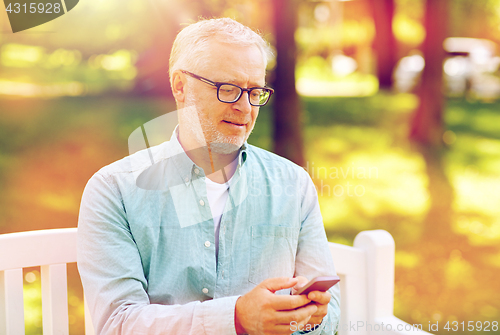 Image of happy senior man texting on smartphone at summer