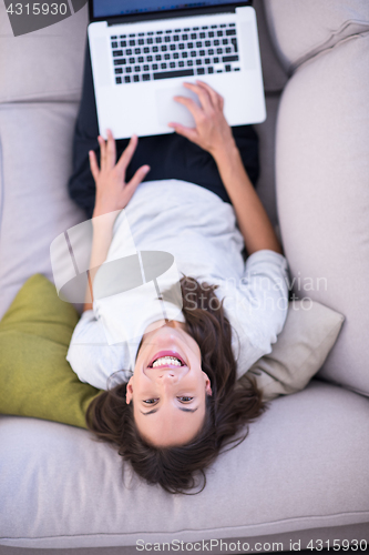 Image of Young woman using laptop at home top view