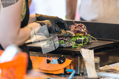 Image of Chef making beef burgers outdoor on open kitchen international food festival event.