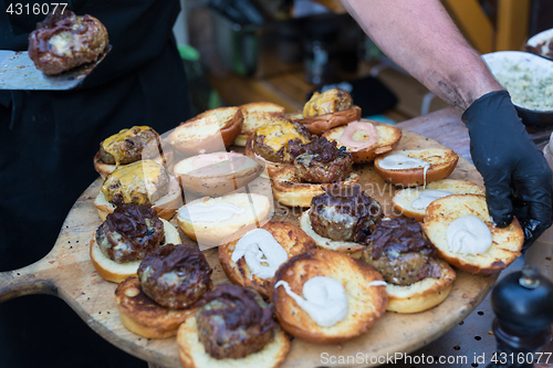 Image of Chef making beef burgers outdoor on open kitchen international food festival event.