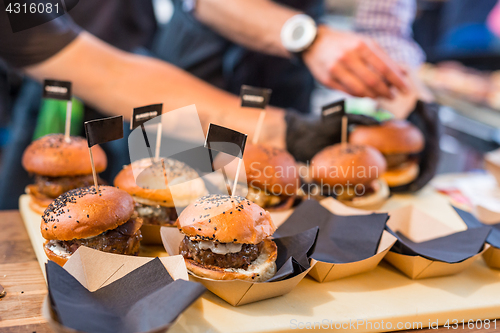 Image of Chef making beef burgers outdoor on open kitchen international food festival event.