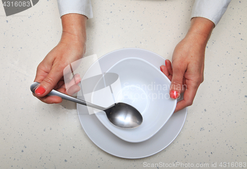 Image of woman holds spoon and plate