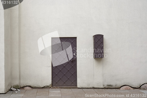 Image of White stucco wall and metal door.