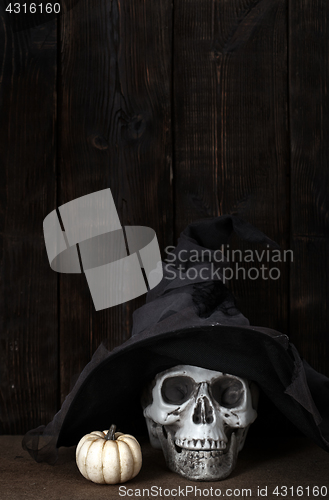 Image of Halloween pumpkin and human skull in witch hat