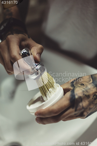 Image of Crop tattooed barber making foam