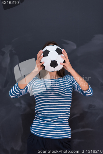 Image of woman holding a soccer ball in front of chalk drawing board